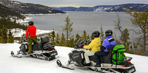 Snowmobilers in front of the Saguenay fjord